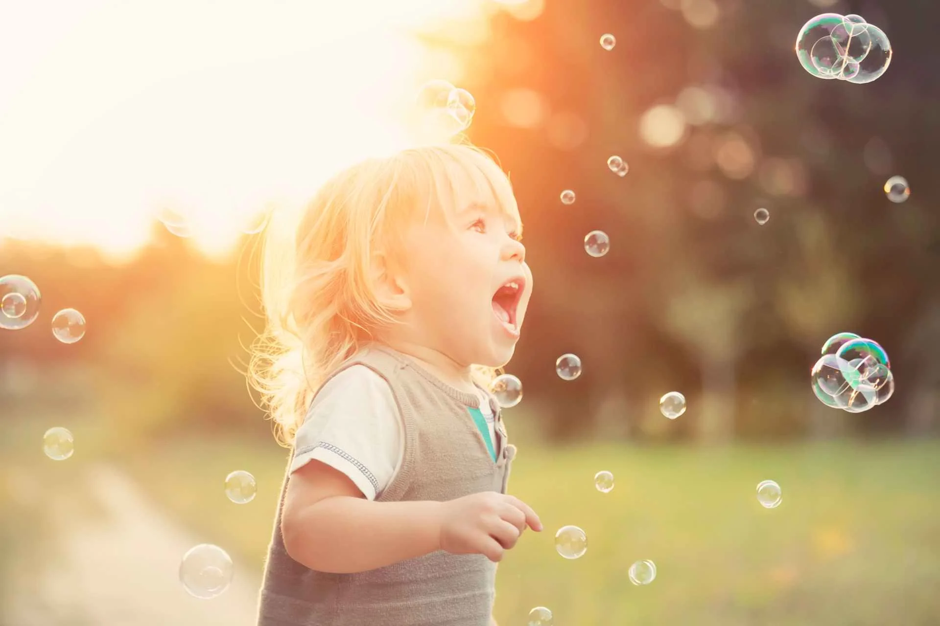 Fröhliches Kleinkind mit Seifenblasen im Abendlicht – Symbolbild für die sanfte Akupunktur für Kinder (Shonishin)